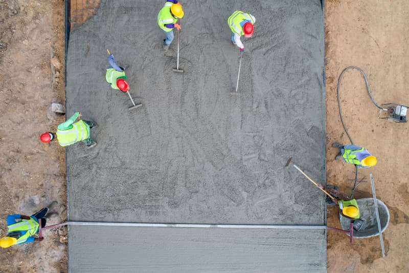 Seven construction workers spreading concrete with shovels