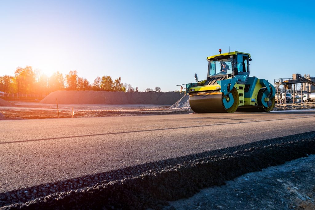 Beautiful sunset above the road rollers working on the new road construction site